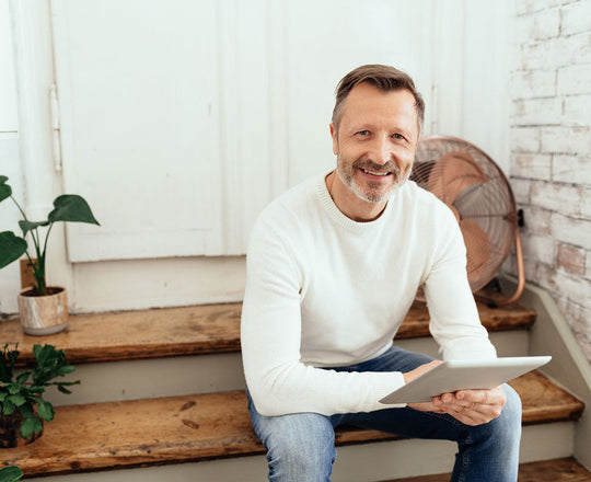 Ein Mann sitzt auf einer Treppe und hält ein Tablet in der Hand