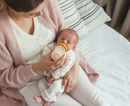 Eine Frau füttert ihr Baby mit einem Fläschchen, während sie es im Arm hält