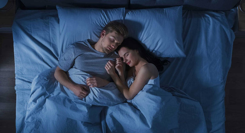 Frau und Mann liegen im Bett und schlafen nebeneinander