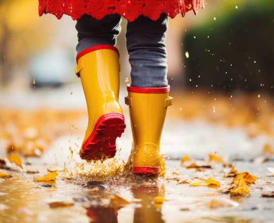 Kind läuft mit Gummistiefel durch Pfützen