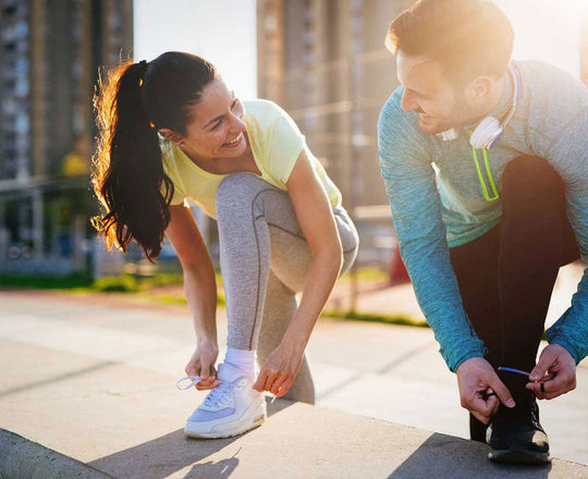 Frau und Mann binden sich die Schuhe, bevor sie joggen gehen