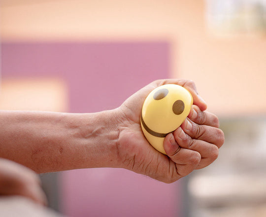 Frau hält einen Anti-Stress-Ball in der Hand und drückt ihn zusammen