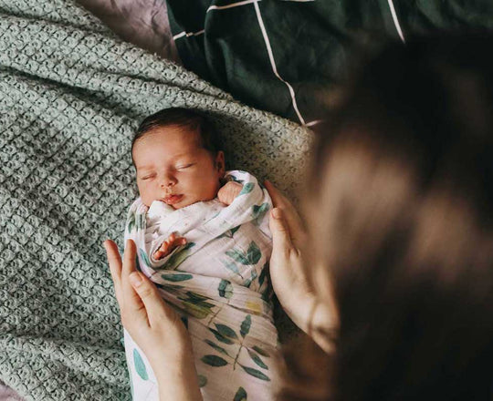 Eine Mutter hält ihr in eine Decke eingewickeltes Baby mit den Händen