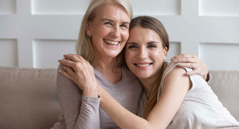 Zwei Frauen sitzen nebeneinander und umarmen sich