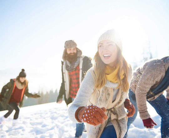 Frauen und Männer lachen gemeinsam im Schnee