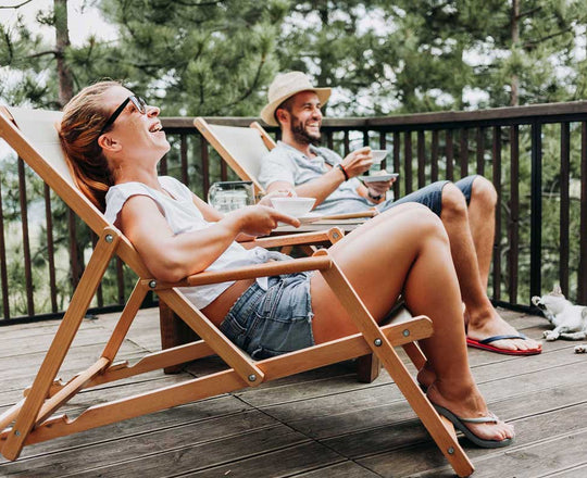 Eine Frau und ein Mann sitzen nebeneinander in Liegestühlen und lachen