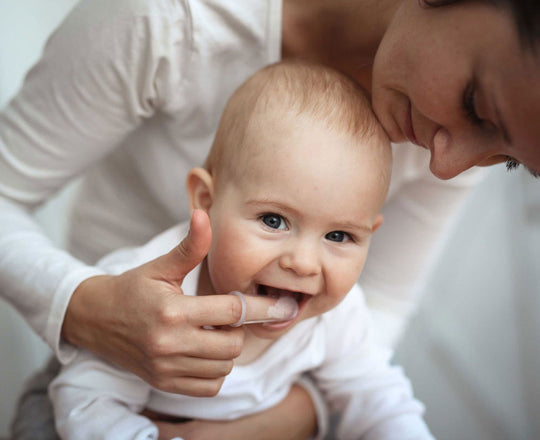 Eine Mutter putzt ihrem Baby vorsichtig die ersten Zähnchen