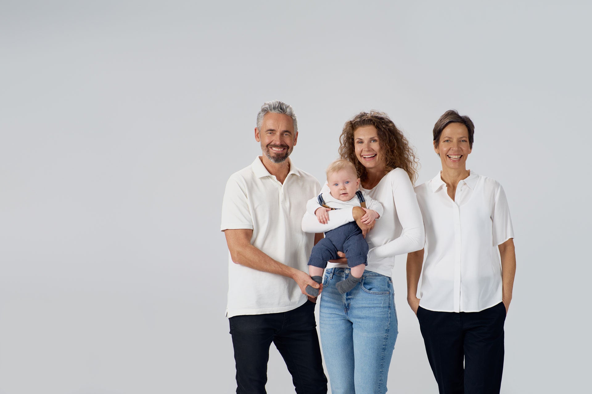 Strahlendes Baby, zwei lachende Frauen und ein lachender Mann