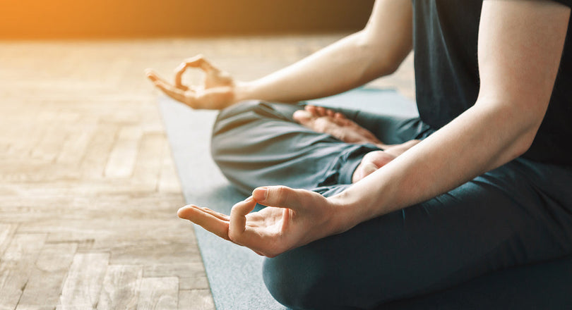 Mann sitzt im Schneidersitz und meditiert