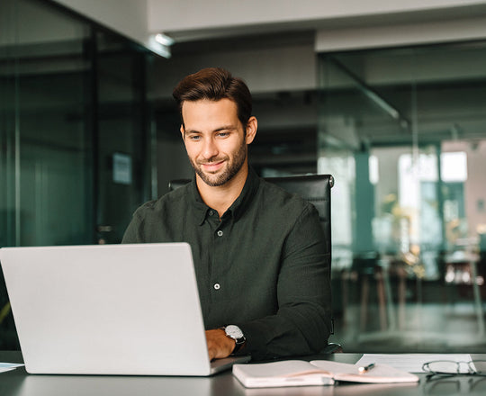 Mann sitzt am Schreibtisch und arbeitet am Laptop