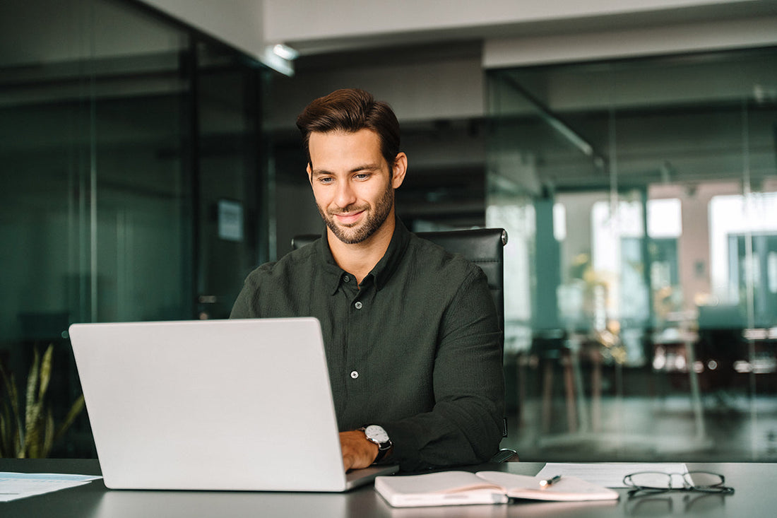 Mann sitzt am Schreibtisch und arbeitet am Laptop