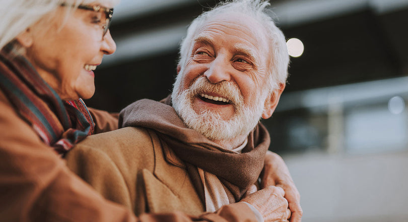 Eine ältere Frau umarmt einen älteren Mann, beide schauen sich an