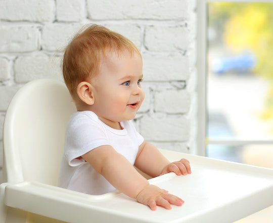 Baby sitzt im Hochstuhl und lacht