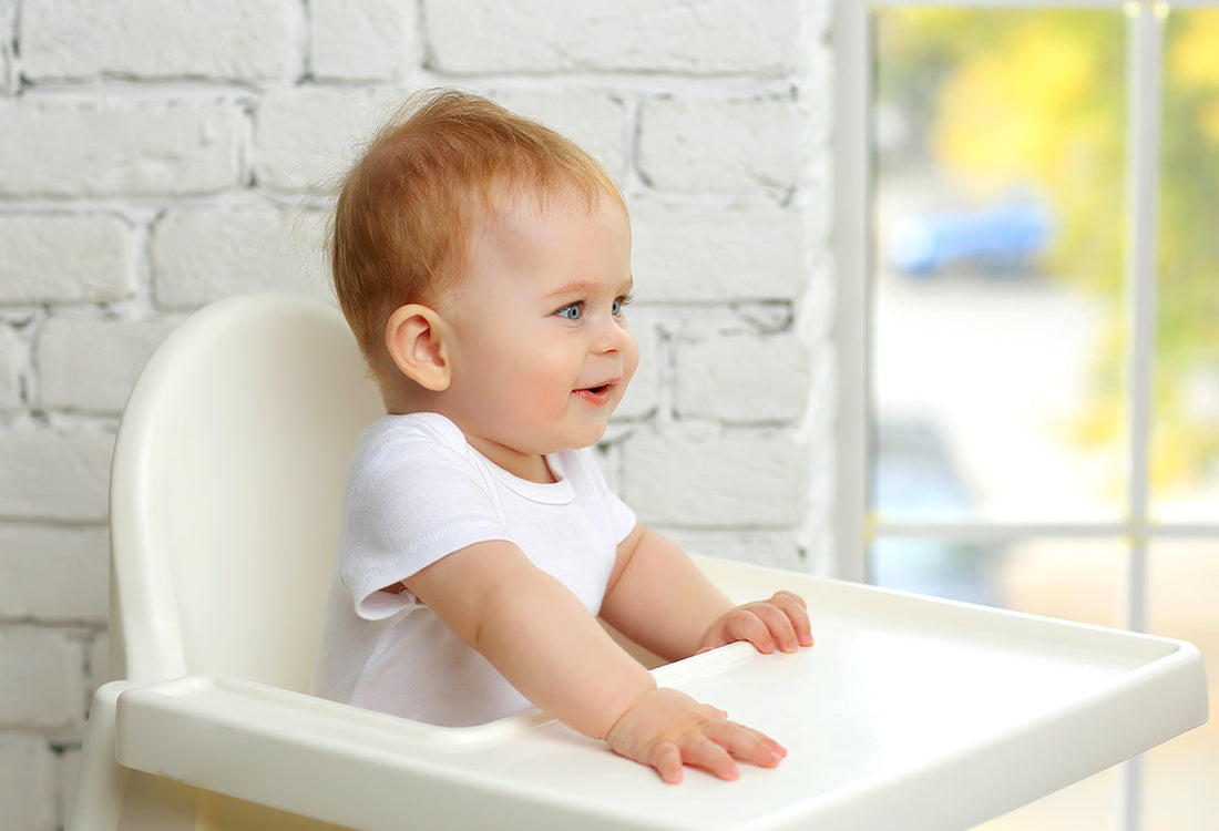 Baby sitzt im Hochstuhl und lacht