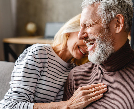 Eine Frau und ein Mann liegen sich in den Armen und lachen