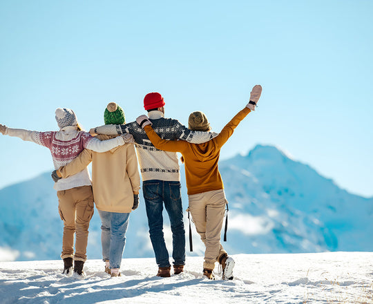 Vier Freunde stehen auf einem verschneiten Berggipfel