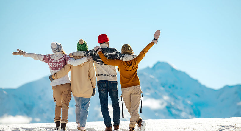 Vier Freunde stehen auf einem verschneiten Berggipfel
