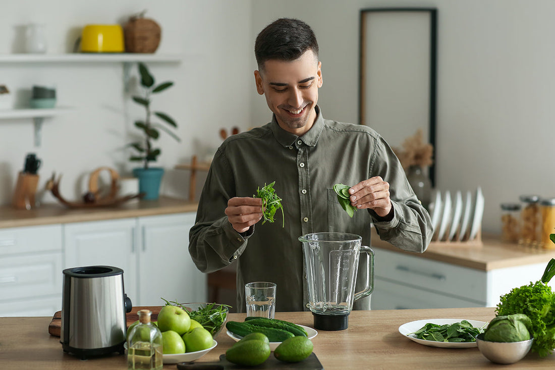 Junger Mann mixt einen grünen Smoothie