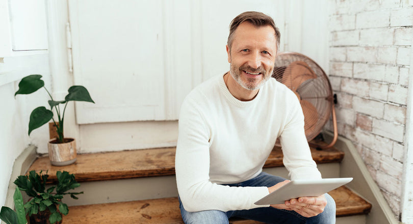 Ein Mann sitzt auf einer Treppe und hält ein Tablet in der Hand