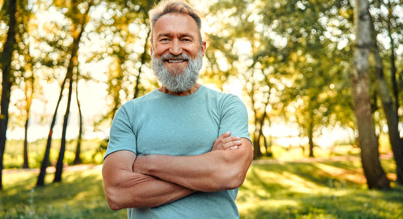 Ein Mann steht mit verschränkten Armen inmitten von grüner Natur