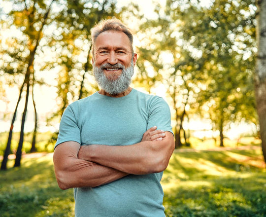 Ein Mann steht mit verschränkten Armen inmitten von grüner Natur