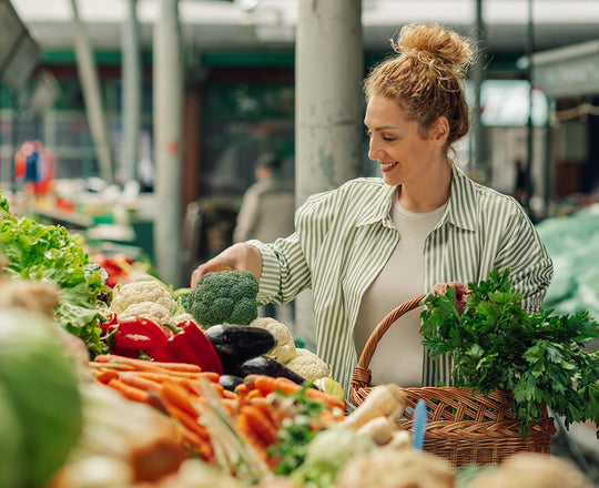 Frau kauft Gemüse auf einem Markt