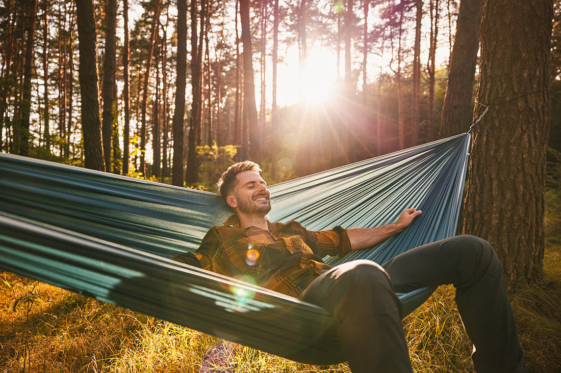 Mann sitzt in einer Hängematte in der Natur