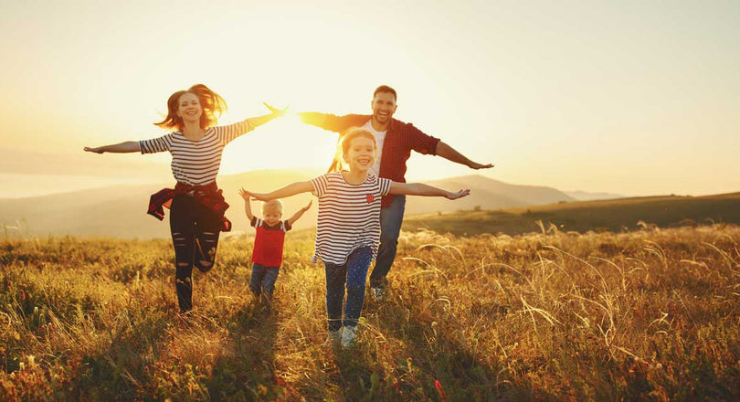 Familie läuft im Sonnenschein über ein Feld