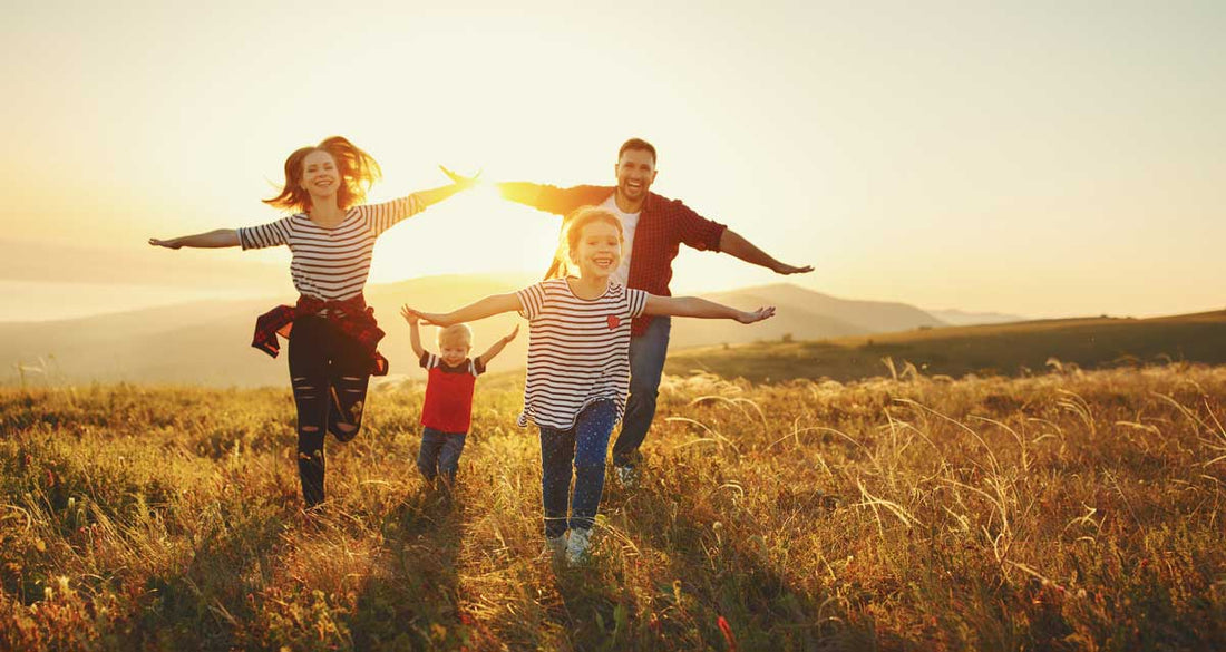 Familie läuft im Sonnenschein über ein Feld