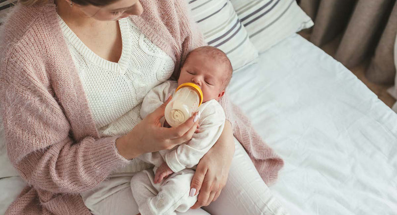 Eine Frau füttert ihr Baby mit einem Fläschchen, während sie es im Arm hält