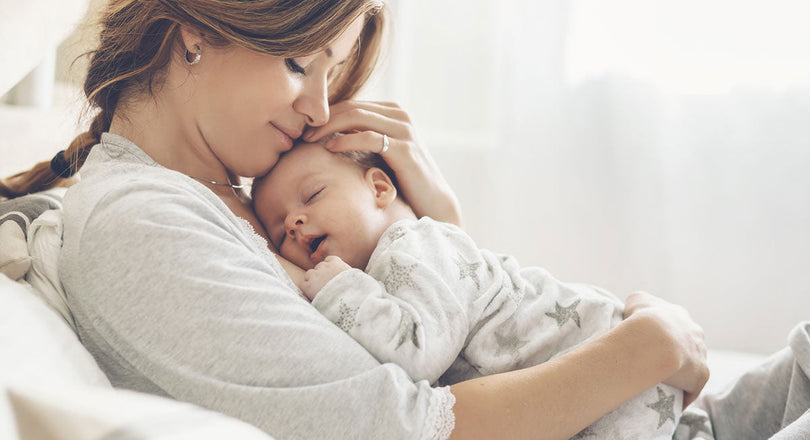 Frau liegt mit einem Baby auf ihrem Bauch