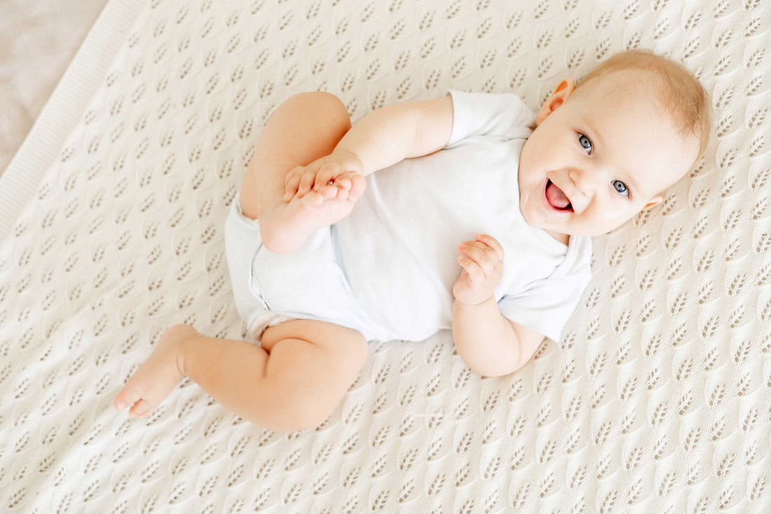 Baby liegt auf einer Decke und lächelt