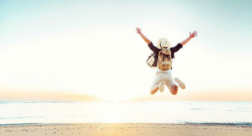 Mann springt am Strand in die Luft