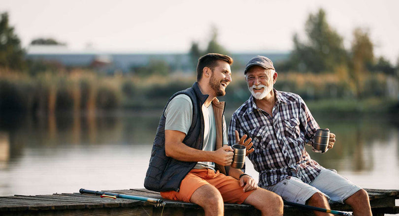 Zwei Männer sitzen an einem Steg am See