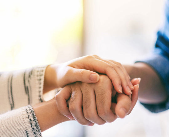 Frau hält die Hände eines Mannes, um ihm Trost zu spenden