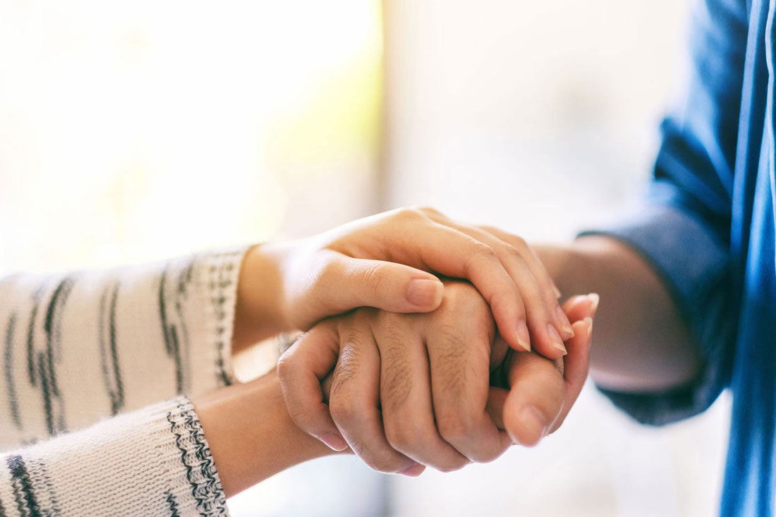 Frau hält die Hände eines Mannes, um ihm Trost zu spenden