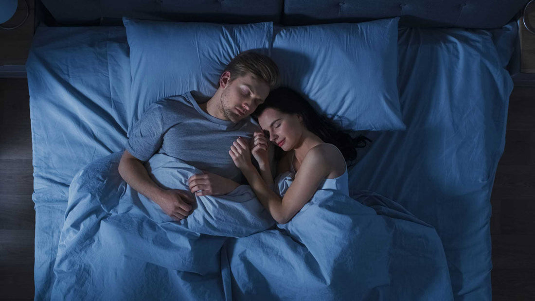 Frau und Mann liegen im Bett und schlafen nebeneinander