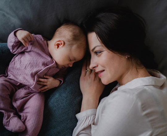 Mama liegt mit ihrem Baby auf dem Bett