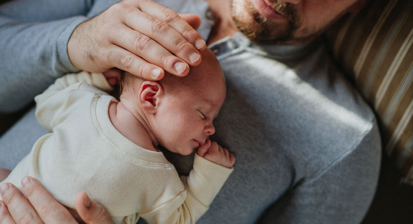 Baby, das auf dem Bauch seines Papas liegt und schläft