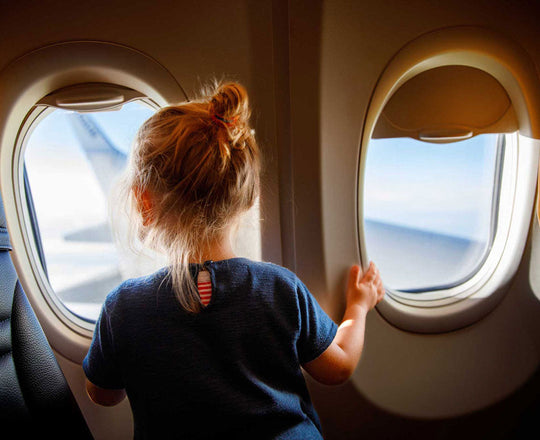Mädchen sitzt am Fenster im Flugzeug und blickt nach draußen