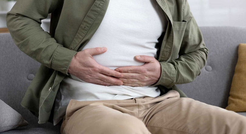 Ein Mann sitzt auf einem Sofa und hält seinen Bauch