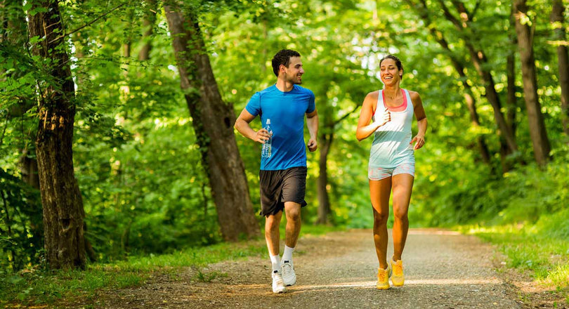 Frau und Mann joggen gemeinsam durch einen Wald