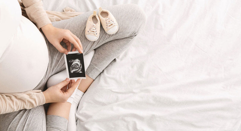 Schwangere Frau hält ein Ultraschallbild in den Händen