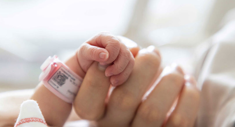 Baby hält den Finger der Mama