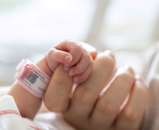  Baby hält den Finger der Mama
