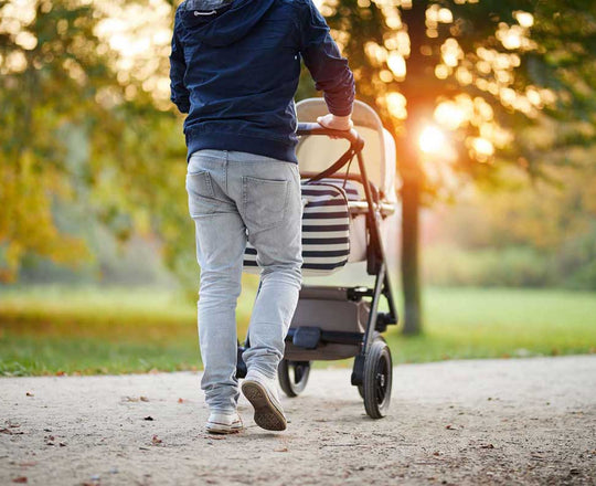 Mann schiebt einen Kinderwagen durch eine natürliche Landschaft