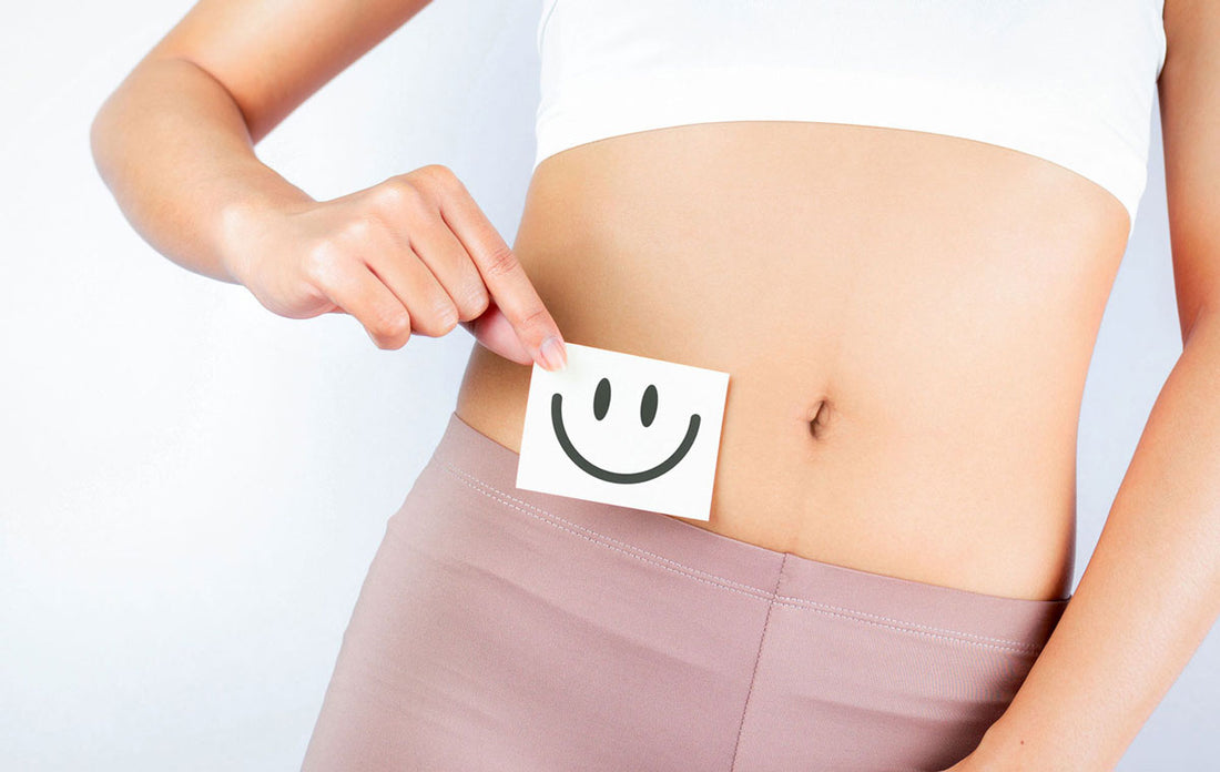 Frau hält einen Zettel mit einem lachenden Smiley vor ihrem Bauch
