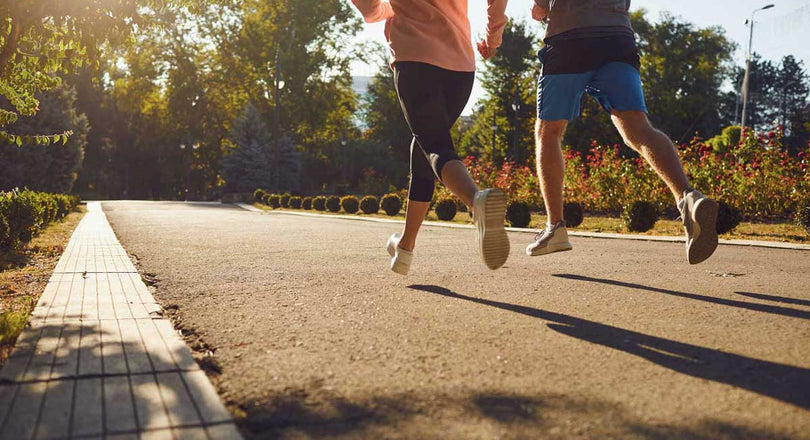 Eine Frau und ein Mann joggen durch einen grünen Park