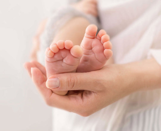 Eine Mama hält behutsam die Füße ihres Babys