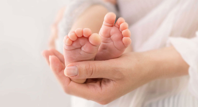Eine Mama hält behutsam die Füße ihres Babys